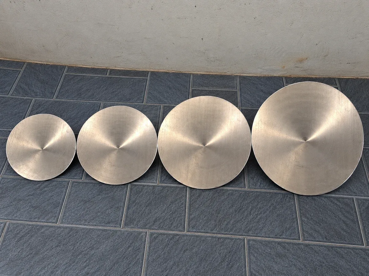 Bốn máng nón bằng nhôm từ nhỏ đến lớn đặt thành một hàng trên nền gạch