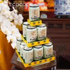 Tháp nước ngọt chữ vạn 3 tầng vuông màu vàng xếp lon bia trên đôn gỗ, thấy rõ khay vuông cắt CNC hình chữ vạn