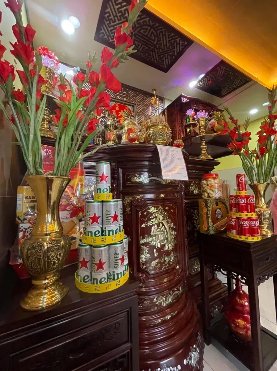 Tháp bia lon 3 tầng và tháp nước ngọt 3 tầng chữ vạn bày trên bàn thờ cạnh bình hoa đồng