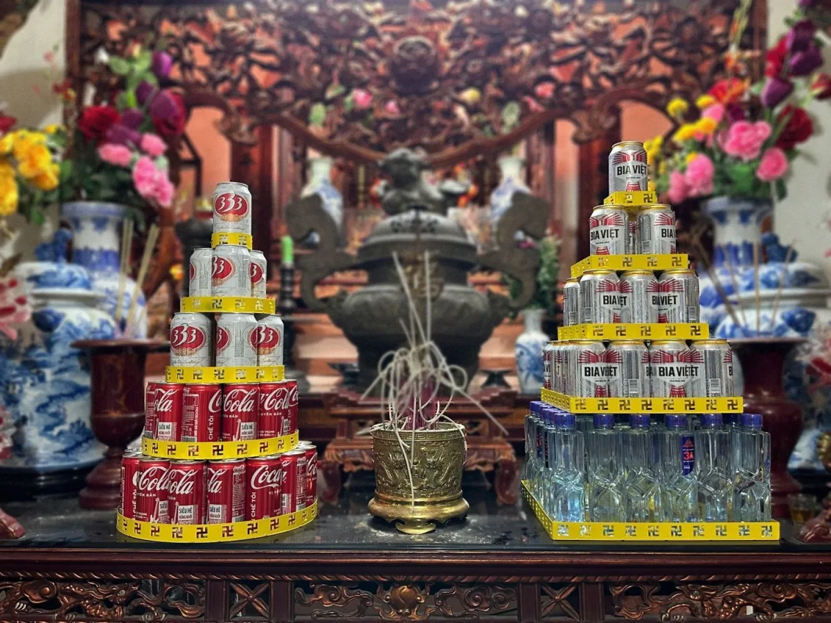 Bàn thờ gia tiên có tháp nước ngọt tròn xếp lon Coca và bia 333 bên trái, tháp vuông xếp bia và chai nước bên phải, giữa là bát hương đồng