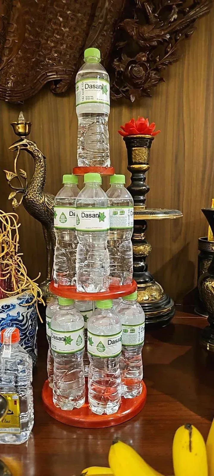 Tháp nước ngọt bằng gỗ tròn xếp chai nước suối Dasani trên bàn thờ gia tiên